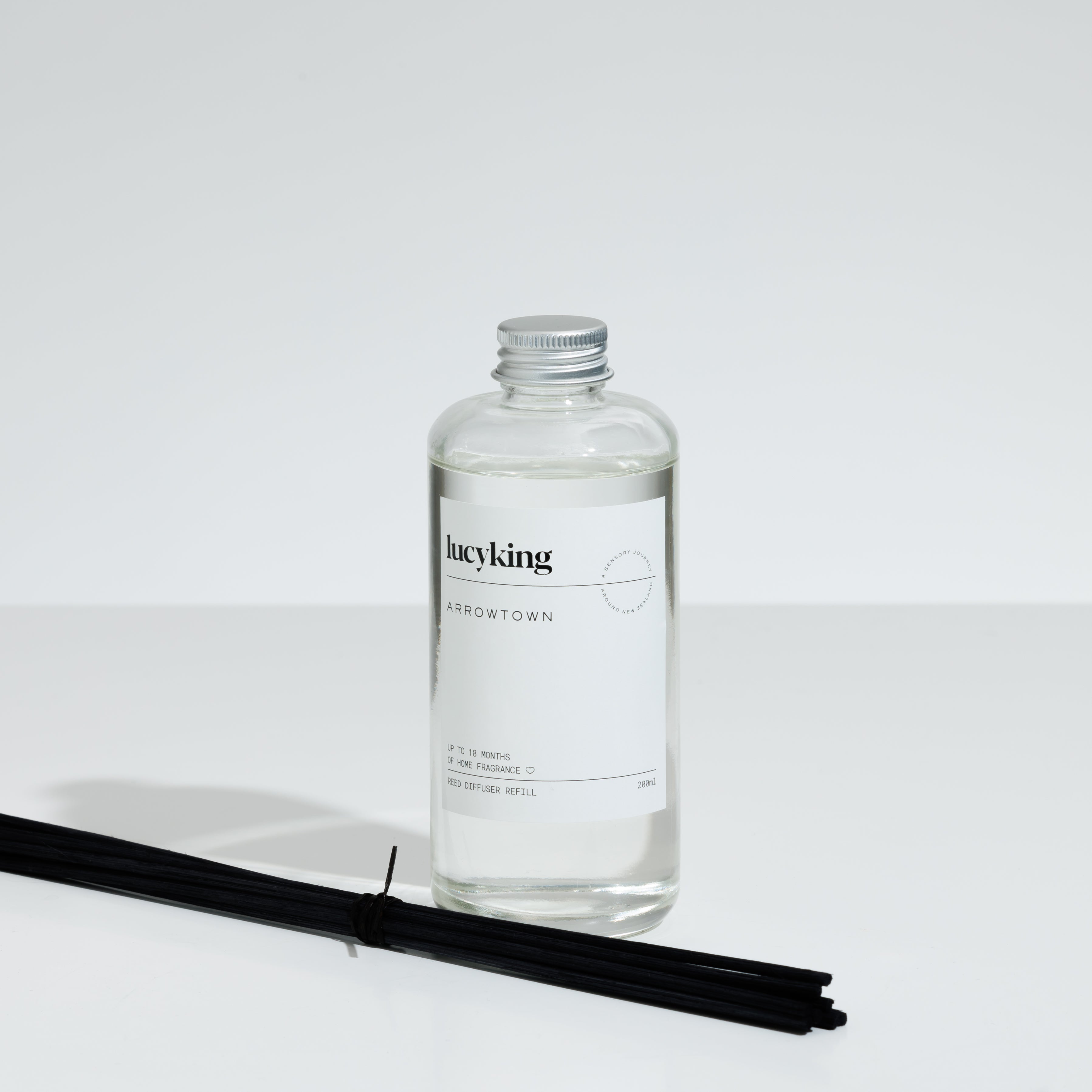 Best selling Arrowtown reed diffuser oil refill in a clear bottle with a brushed aluminium screwtop lid and reeds