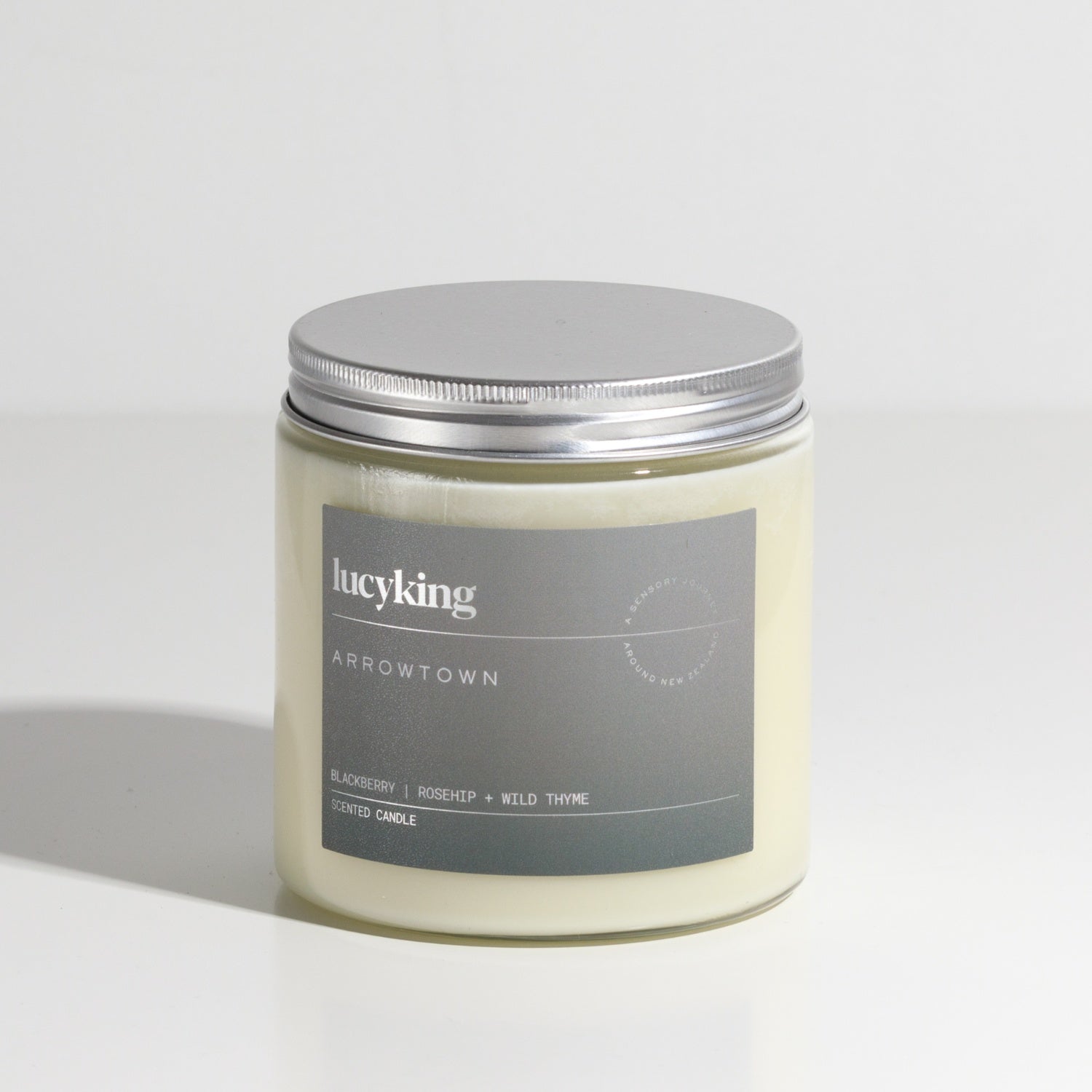 Large best selling Arrowtown soy wax scented candle in a clear glass jar with grey label and brushed aluminium silver screwtop lid