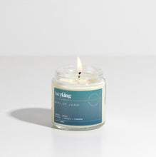Load image into Gallery viewer, Small signature fragrance Bird Of Juno soy wax scented candle with a burning wick in a clear glass jar with teal label

