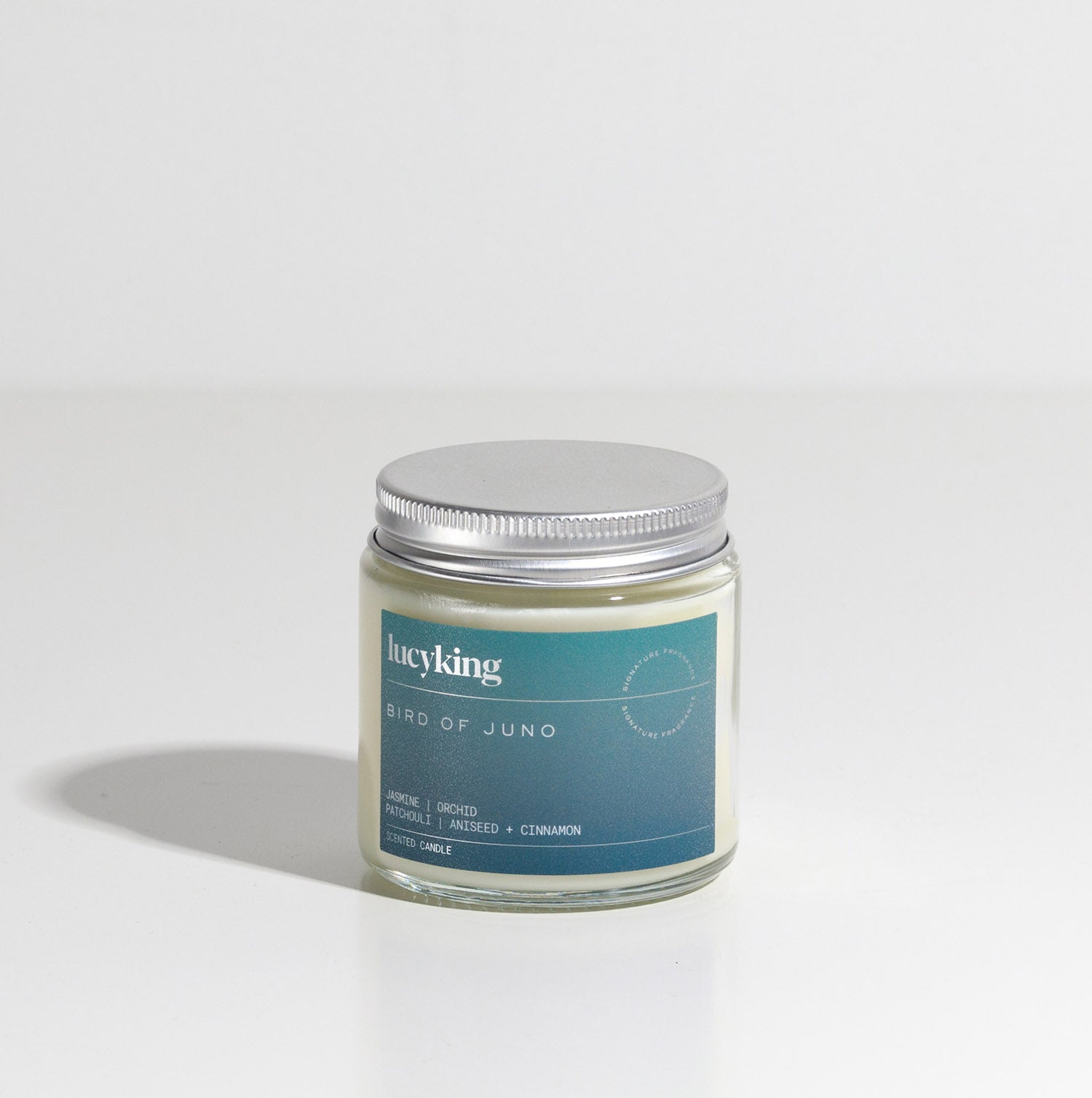 Small signature fragrance soy wax scented candle in a clear glass jar with grey label and brushed aluminium silver screwtop lid