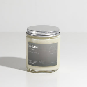 Medium best selling Arrowtown soy wax scented candle in a clear glass jar with grey label and brushed aluminium silver screwtop lid