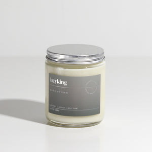 Medium best selling Arrowtown soy wax scented candle in a clear glass jar with grey label and brushed aluminium silver screwtop lid